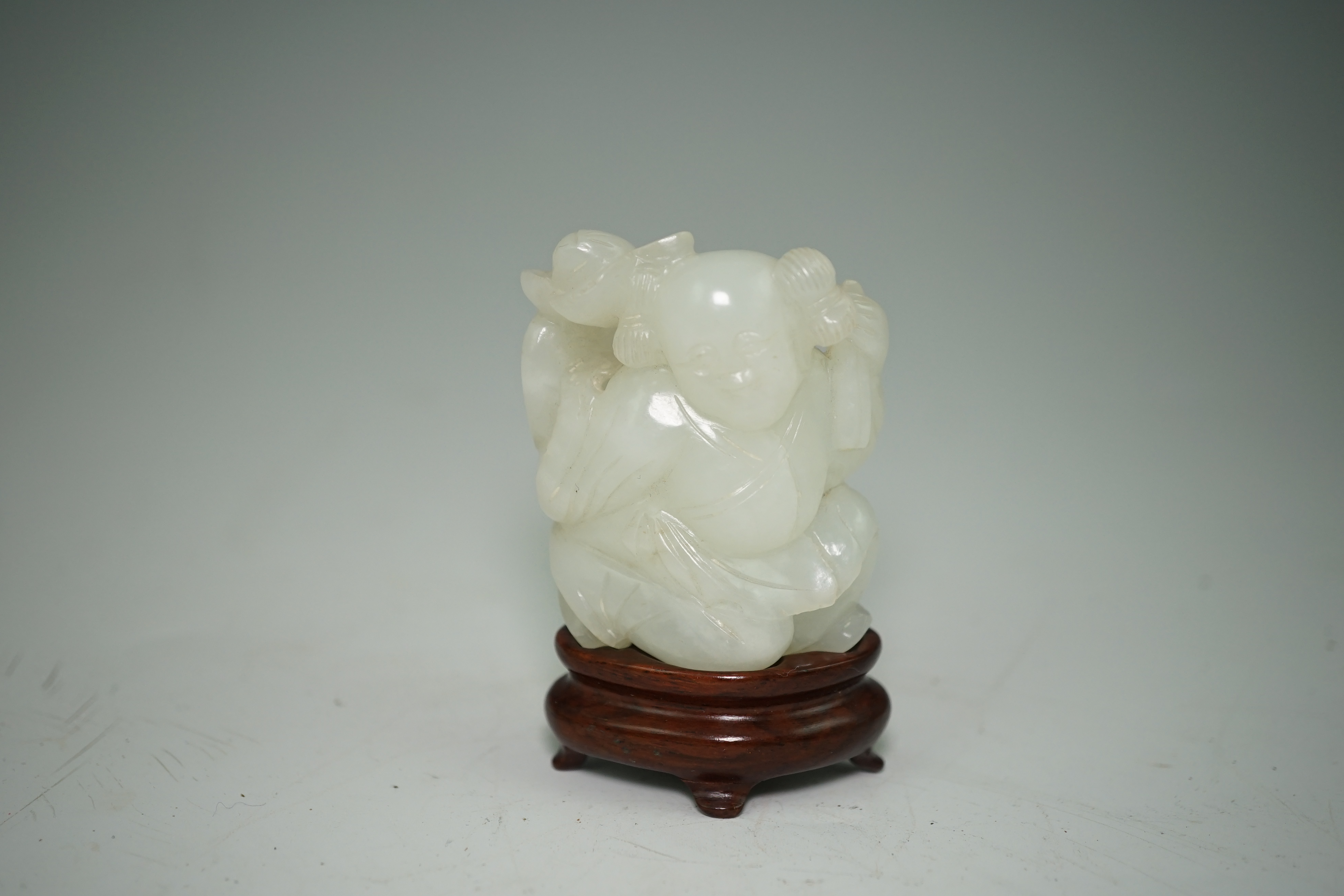 A Chinese white jade figure of a kneeling boy holding lingzhi fungus, 19th century